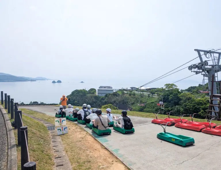八代海を望むスタート地点でローラーリュージュに乗る人たち