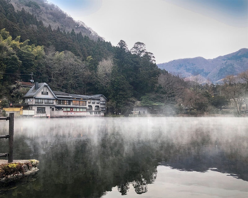 朝霧が湖面を覆う由布院の金鱗湖と湖畔の建物